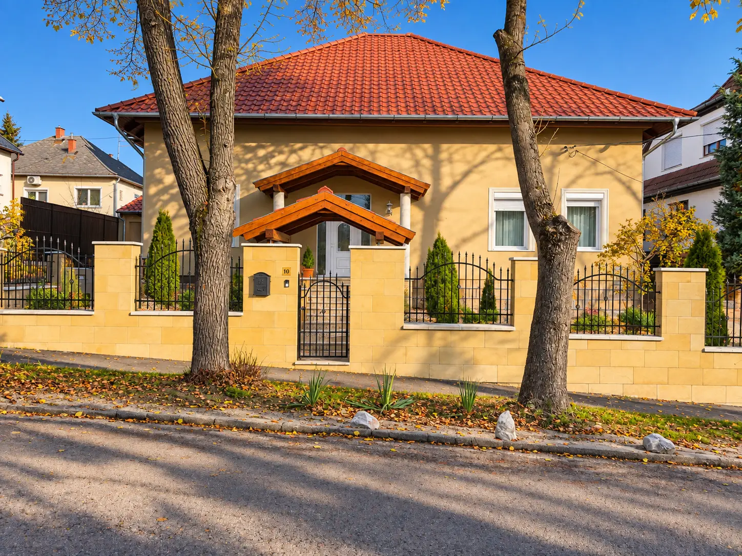 Felújított családi ház kőburkolatú kerítéssel és kovácsoltvas kapuval